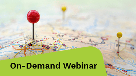 Close-up of a map with a red pushpin marking a location, with a yellow pushpin in the background.