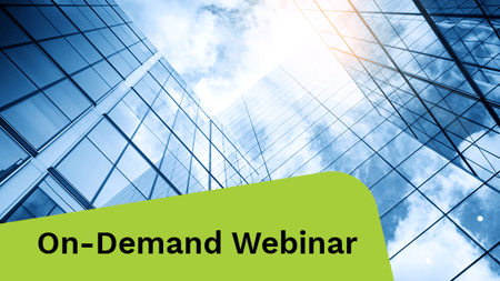 View of a contemporary glass skyscraper reflecting the blue sky.