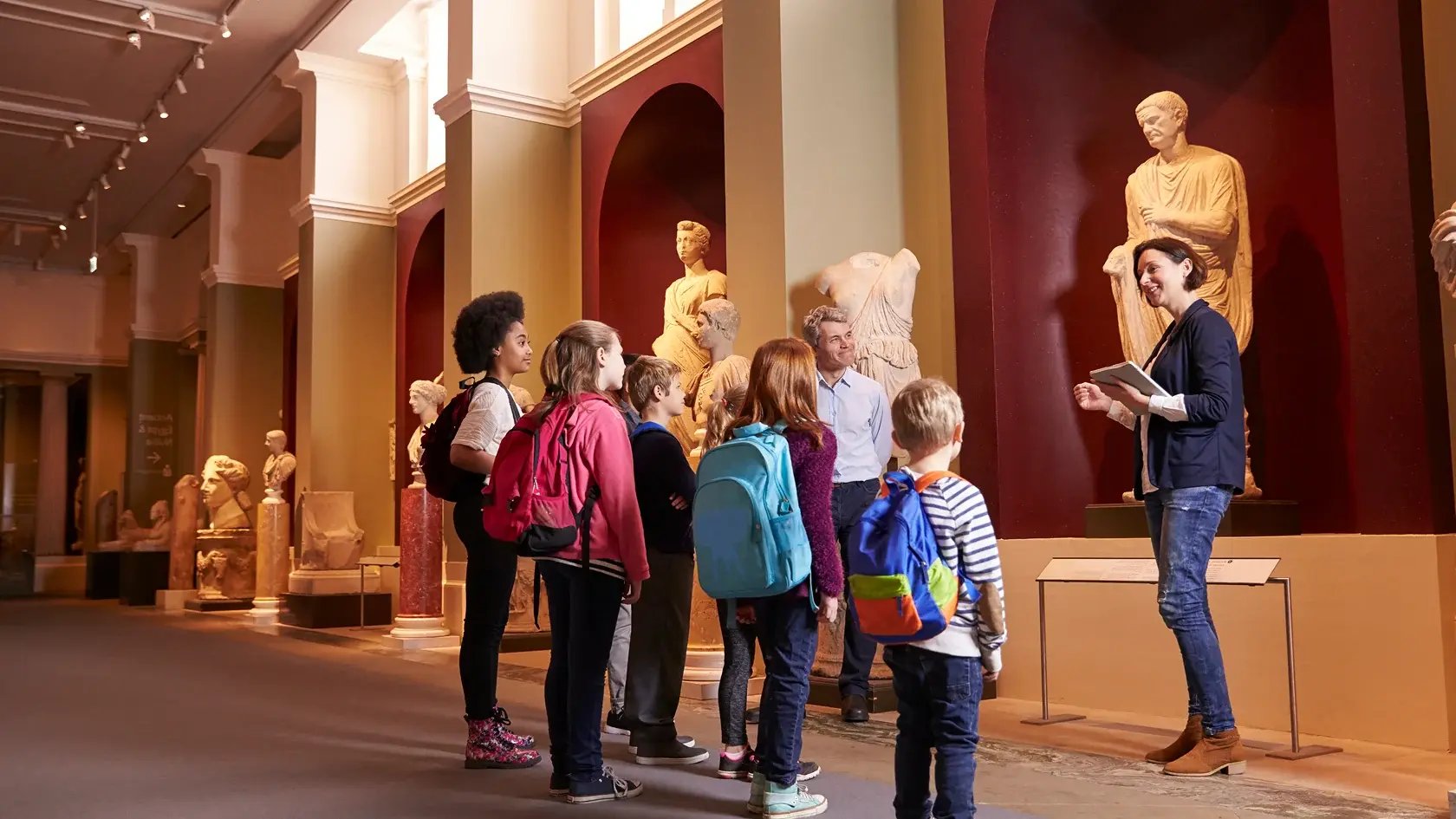 Pupils And Teacher On School Field Trip To Museum With Guide