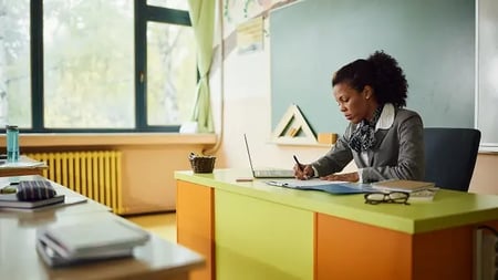 Young female teacher reviews classroom materials from publishers at elementary school. 