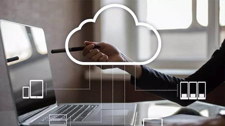 person at desk with cloud icon floating
