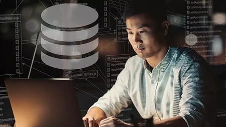 Man sitting in front of a computer in a dark room working on databases