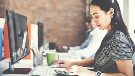 woman in finance career sitting at a desk on a computer 