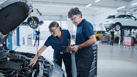 mechanics examining a vehicle in a service shop
