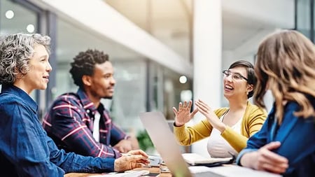 Group of educators sitting at a table, engaged in a discussion with laptops and documents in front of them