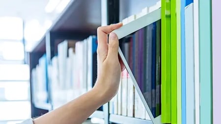 Person choosing tablet from a bookshelf