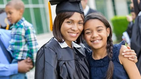 woman in graduation outfit poses with her daughter