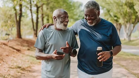 Two senior friends walking together in public park