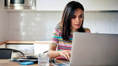 Close-up of a woman using laptop while sitting at table