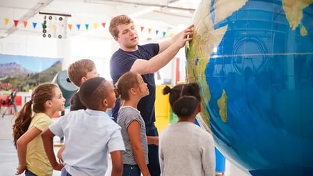 Kids watch presentation with giant globe at a social studies classroom