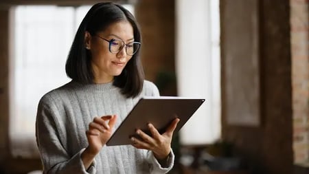 Smiling asian businesswoman reading her plans on digital tablet in the office.