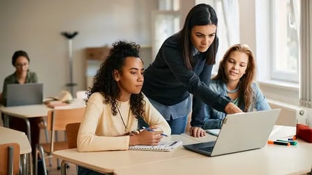 IT teacher and her students using laptop during computer class in high school.