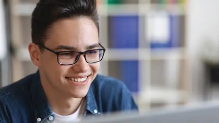 Closeup Shot Of Happy Young Man In Glasses Working With Laptop In Office