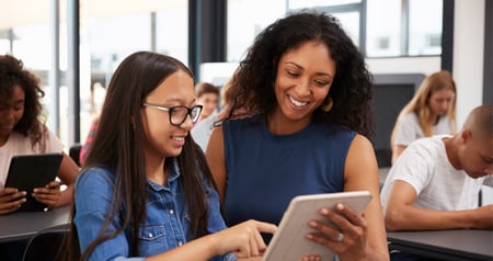 Student and teacher looking at a tablet smiling
