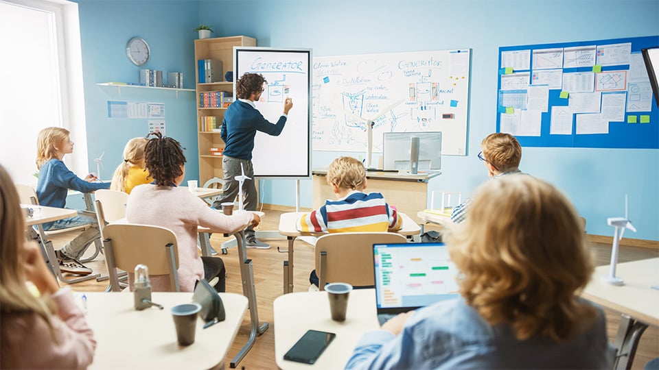 Elementary School Physics Teacher Uses Interactive Digital Whiteboard to Show to a Classroom full of Smart Diverse Children how Renewable Energy Works. Science Class with Kids Listening