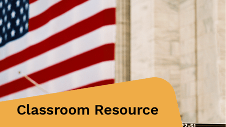 A large American flag hangs behind a Wall Street sign in front of a classical building with columns.