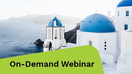 White Cycladic architecture with bright blue domes stands above the deep blue Aegean Sea overlooking distant cliffs in Santorini, Greece.