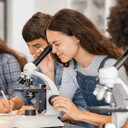 students performing experiment using microscope in science lab