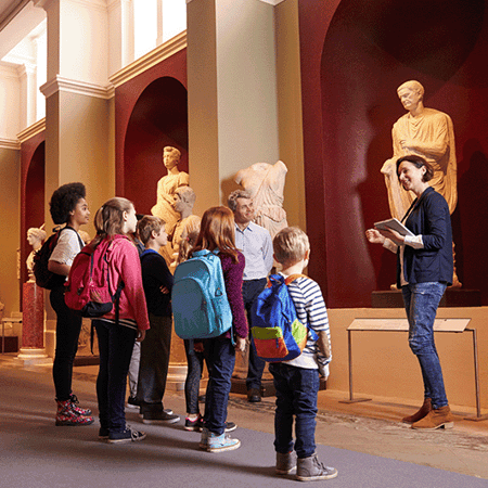 Pupils And Teacher On School Field Trip To Museum With Guide